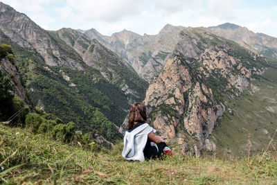 Rear view of woman sitting against mountains