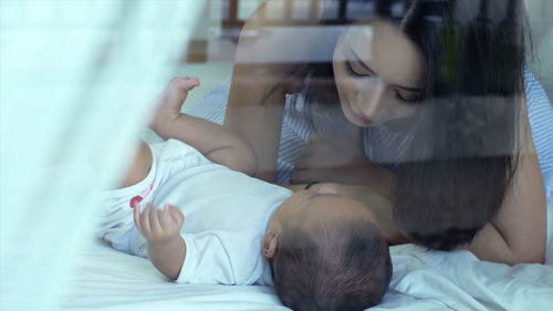 Mother looking at cute son on bed at home