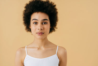 Portrait of young woman against beige background