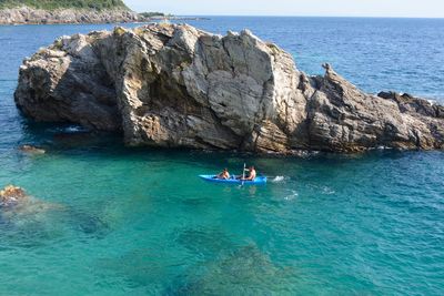 People sailing by rock in sea