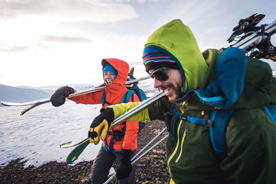 Woman and man laughing while walking with skis in iceland