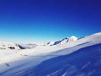 Scenic view of snowcapped mountains against clear blue sky