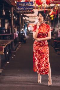 Thoughtful woman in red dress standing at market