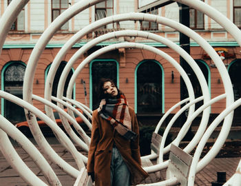 Portrait of smiling young woman standing against built structure