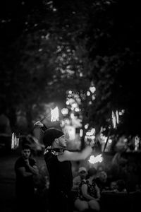 People standing by illuminated tree at night