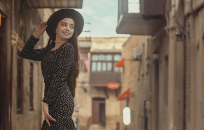 Portrait of young woman standing in city