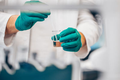 Midsection of scientist holding flask in laboratory