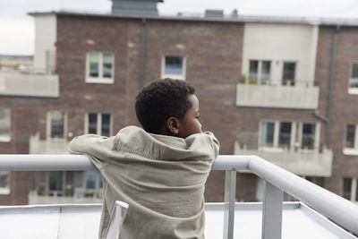 Rear view of boy standing on balcony