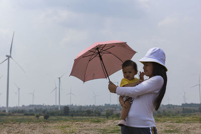 A young mother and her lovely little daughter are at a windmill field.