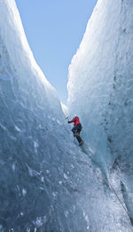 Woman climbing out of glacier cave / sólheimajökull glacier in iceland