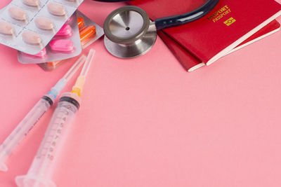 High angle view of medicines and passports on pink background