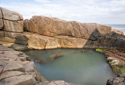 Rock formations by sea against sky