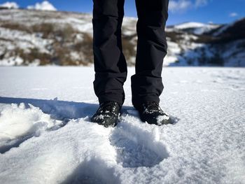 Focus on man wearing black hiking boots walking in the snow