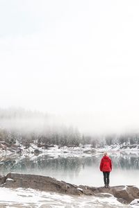 Rear view of woman standing on lakeshore