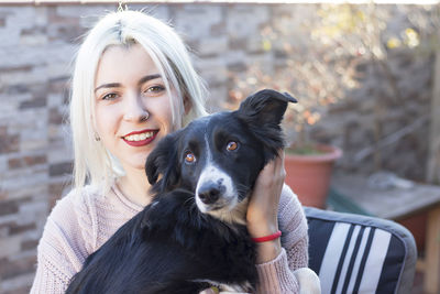 Portrait of smiling woman with dog sitting on chair outdoors