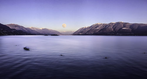 Scenic view of sea and mountains against clear blue sky