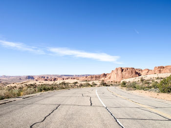 Road leading towards mountains against blue sky