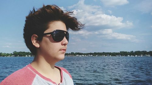 Man in sunglasses by sea against sky during sunny day