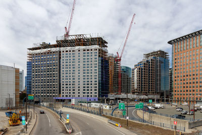 Construction site by buildings against sky in city. highway, mass pike, boston 