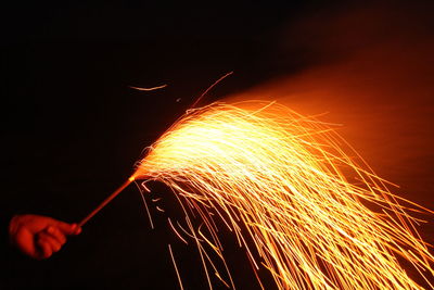 Blurred image of person holding fireworks against orange sky