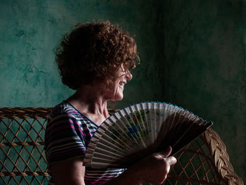 Woman looking away while holding hand fan