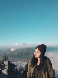 Young woman standing on mountain against sky during winter