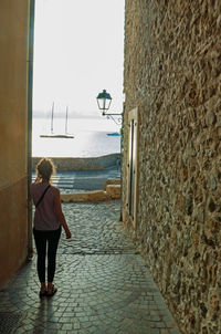 Rear view of woman walking on footpath against sky