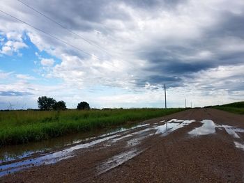 Road amidst field against sky