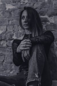 Low angle view of thoughtful young woman sitting against wall