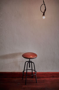 Low angle view of illuminated lamp on table against wall