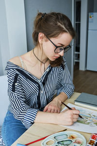 Millennial girl draws fabulous images on paper while sitting at home