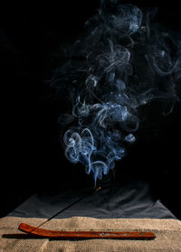 Close-up of emitting smoke against black background