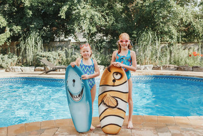 Portrait of smiling girls by swimming pool