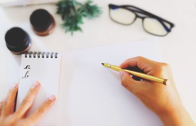 Calligraphy expert holding fountain pen over paper on table