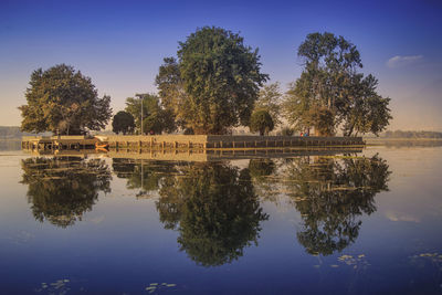 Reflection of trees in lake against blue sky