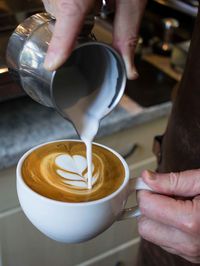 Cropped image of hand pouring coffee in cup