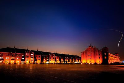 Illuminated buildings in city against sky at night