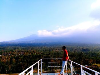 Young man standing on observation point looking at landscape