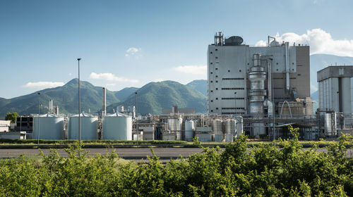 Factory by mountains against sky