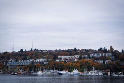 Sailboats in river by buildings against sky