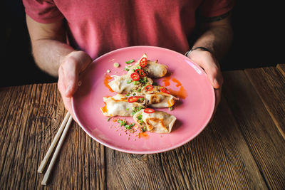 Close-up of hand holding salad in plate on table