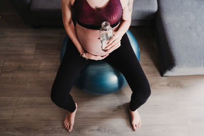 Low section of pregnant woman exercising while sitting at home