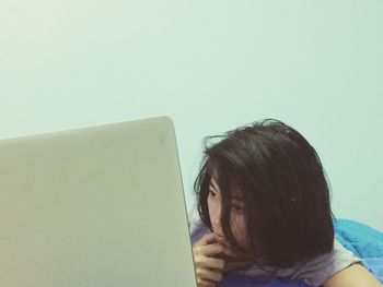 Young woman looking away against white wall