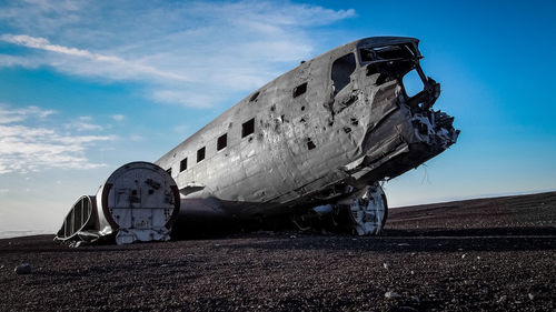 Damaged airplane on field against sky