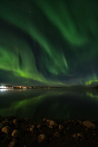 Aurora borealis over river against sky at night