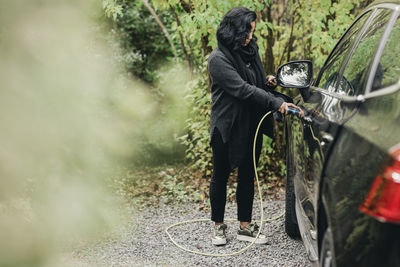 Full length of mid adult woman charging electric car