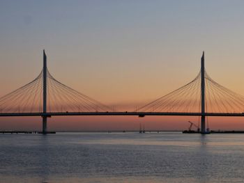 Suspension bridge over sea against sky during sunset