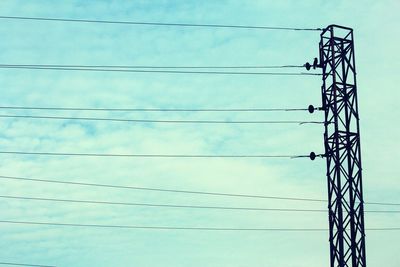 Low angle view of electricity pylon against blue sky