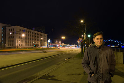 Portrait of man standing on road at night