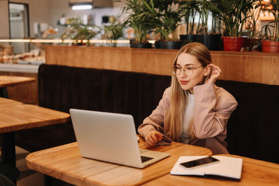 A business woman with glasses works online using a laptop. a student studies online sitting in cafe